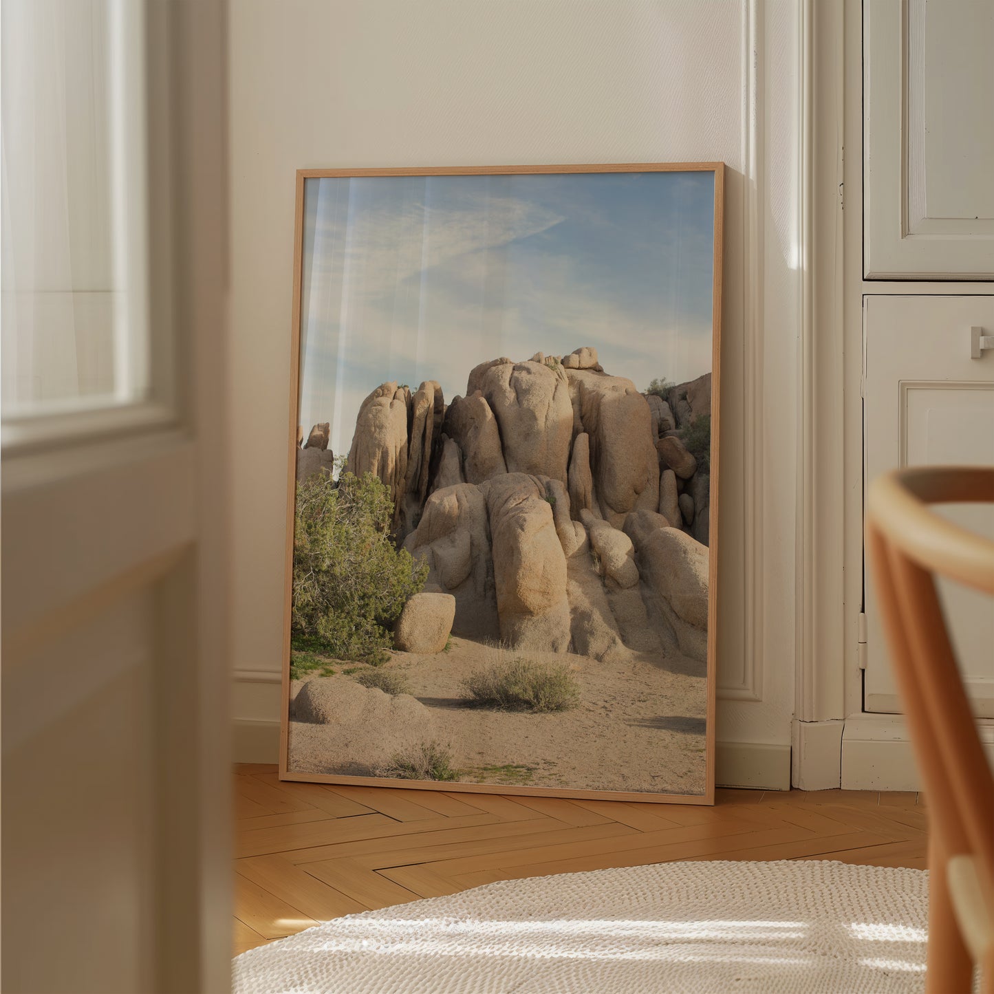 Framed photograph titled JOSHUA TREE 2002 showing sunlit desert rock formations and native brush in a minimalist interior.