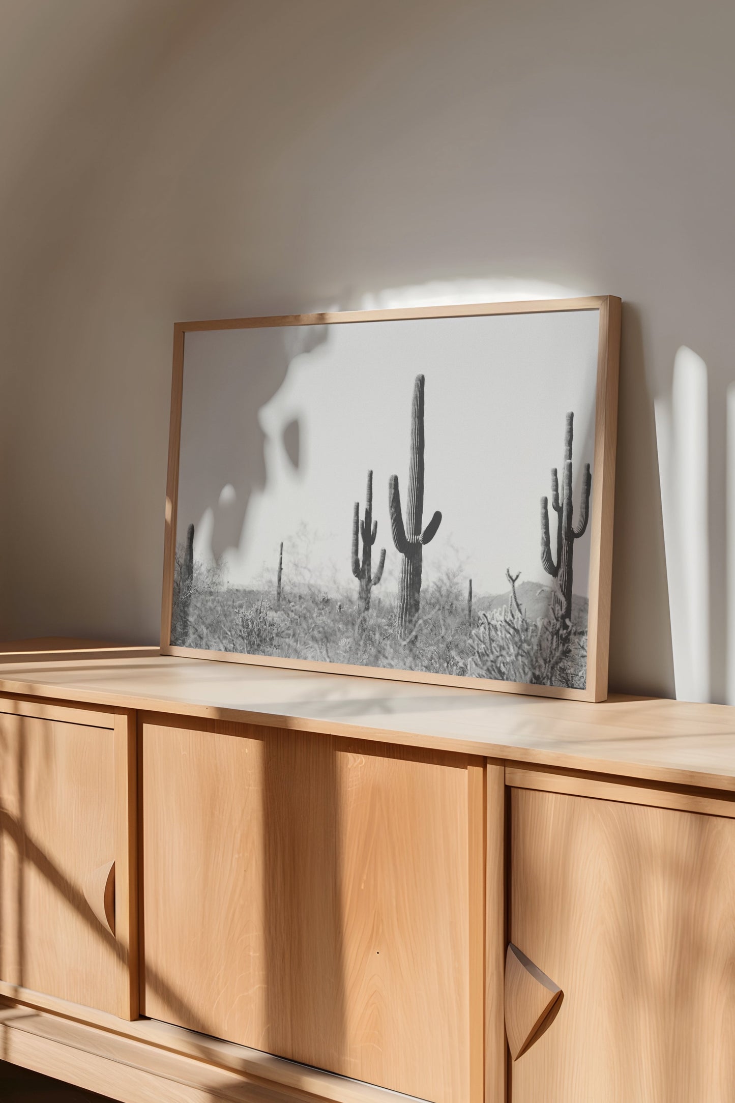 WiLD WiLD black and white saguaro cactus print in minimalist frame on wooden cabinet in modern boho room.
