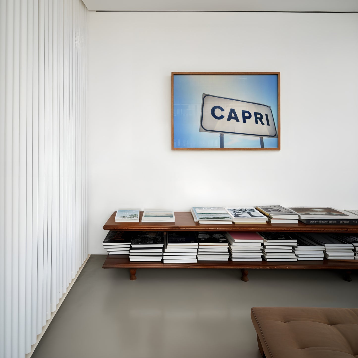 CAPRi framed print featuring a minimalist Capri sign under a bright Mediterranean sky in a modern living room.