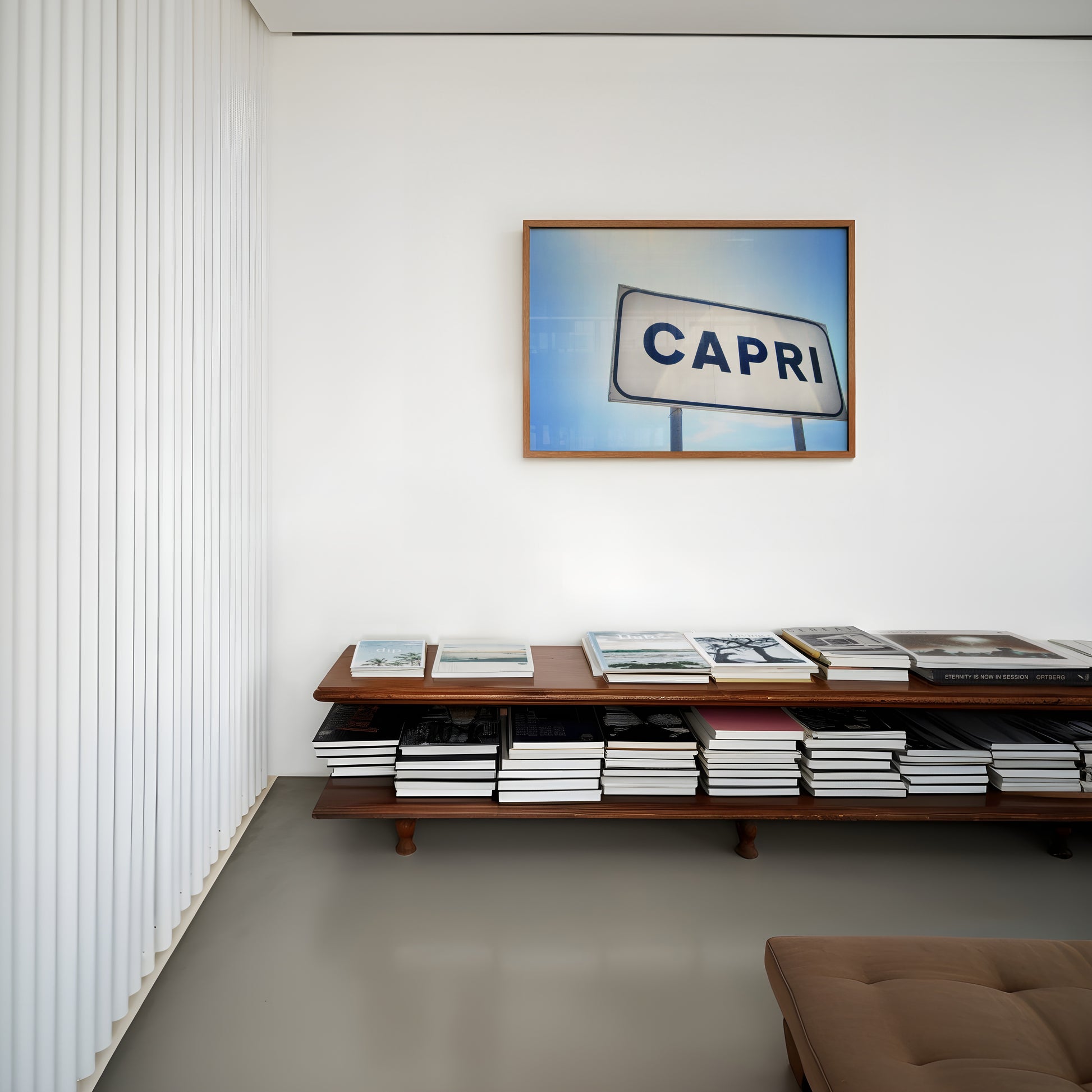 CAPRi framed print featuring a minimalist Capri sign under a bright Mediterranean sky in a modern living room.