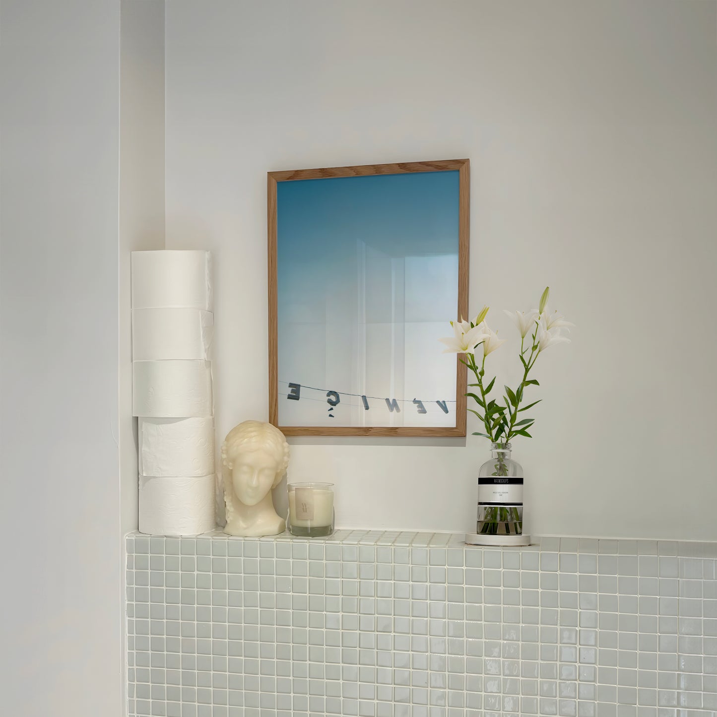 Framed "BACKWARDS" print showing reversed Venice sign against blue sky, styled in minimalist modern interior.