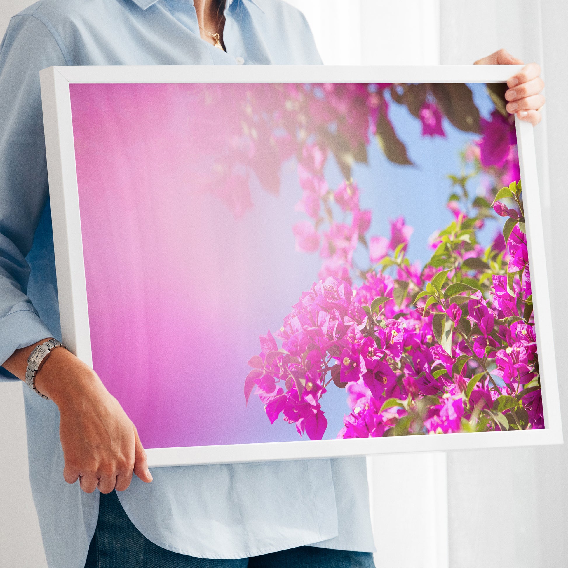 Person holding framed floral photo titled BUCKiNGHAM ROAD with vibrant pink bougainvillea under blue sky.