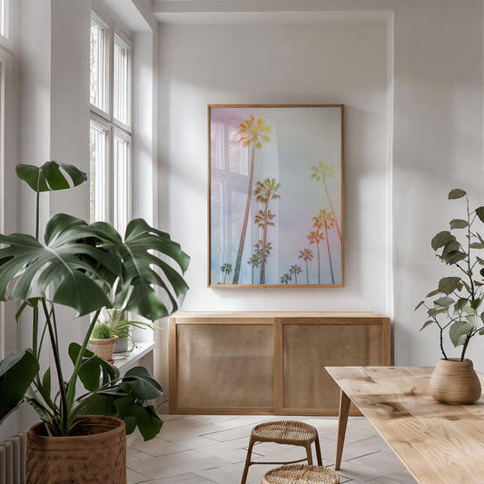 CARAMELO framed print of pastel California palm trees in a bright, airy room with natural wood furniture and plants.