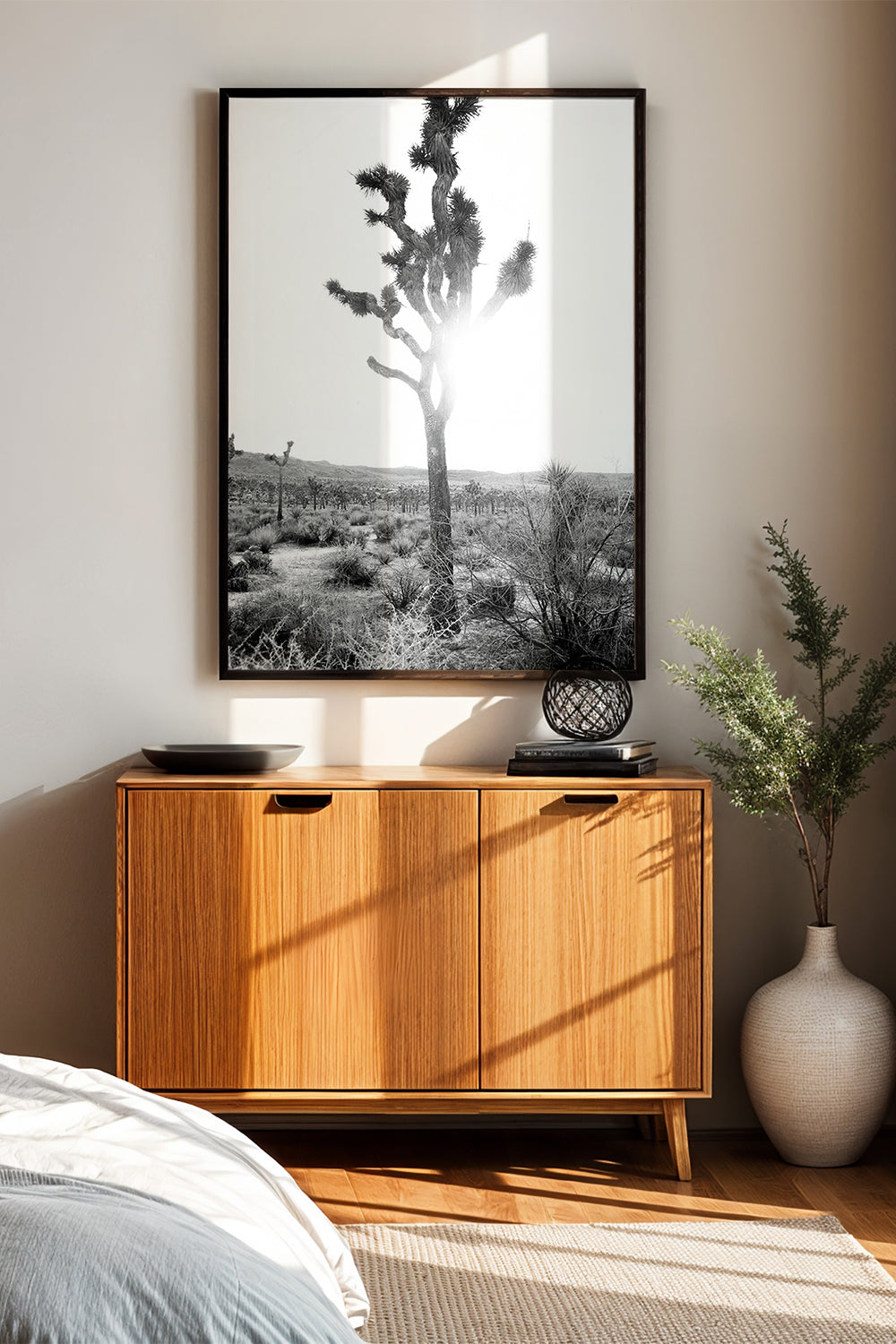 DESPERADO black-and-white photo of a sunlit Joshua tree in desert, framed and displayed above a wooden sideboard.