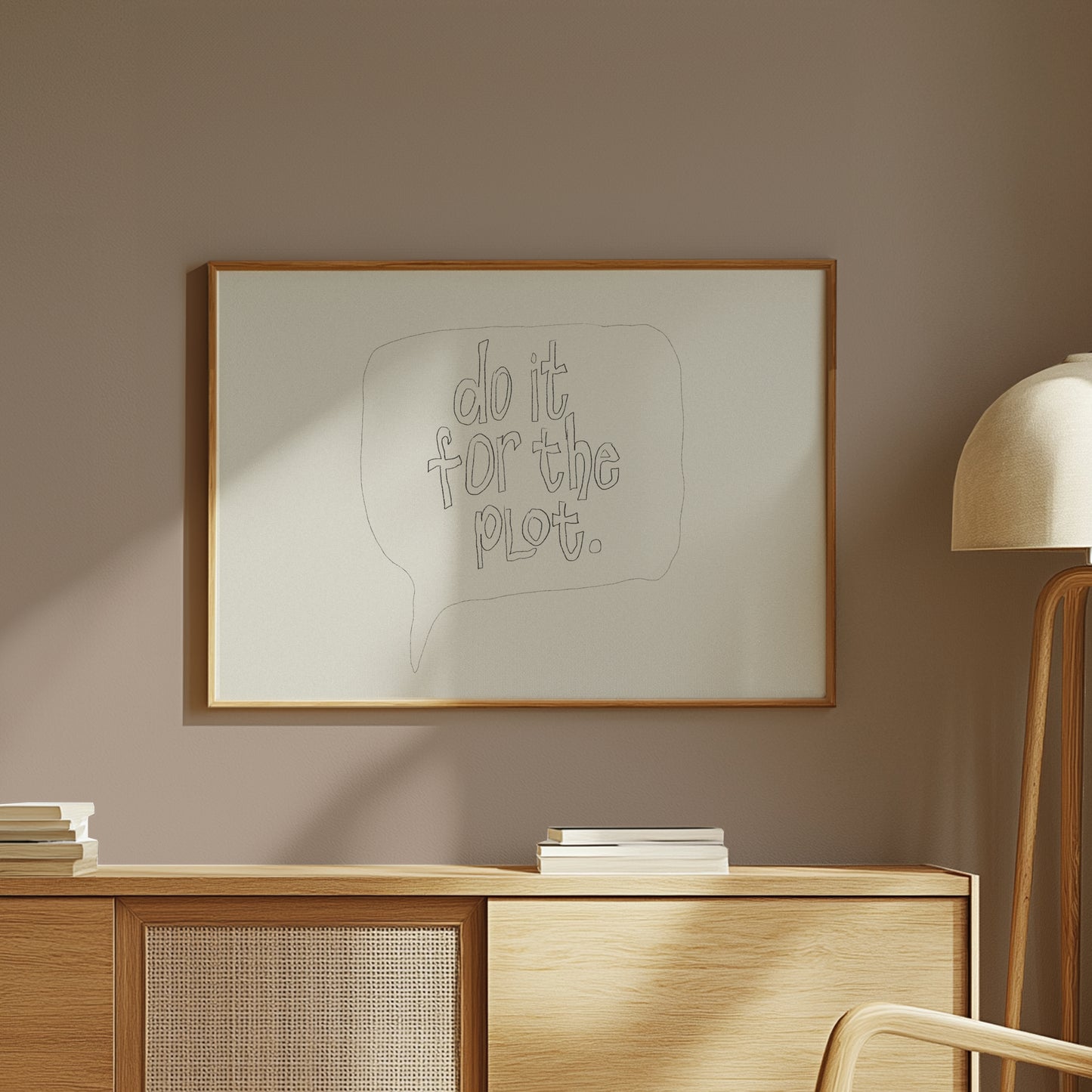 Framed "DO IT FOR THE PLOT" minimalist black line art poster above wooden cabinet in cozy modern room.