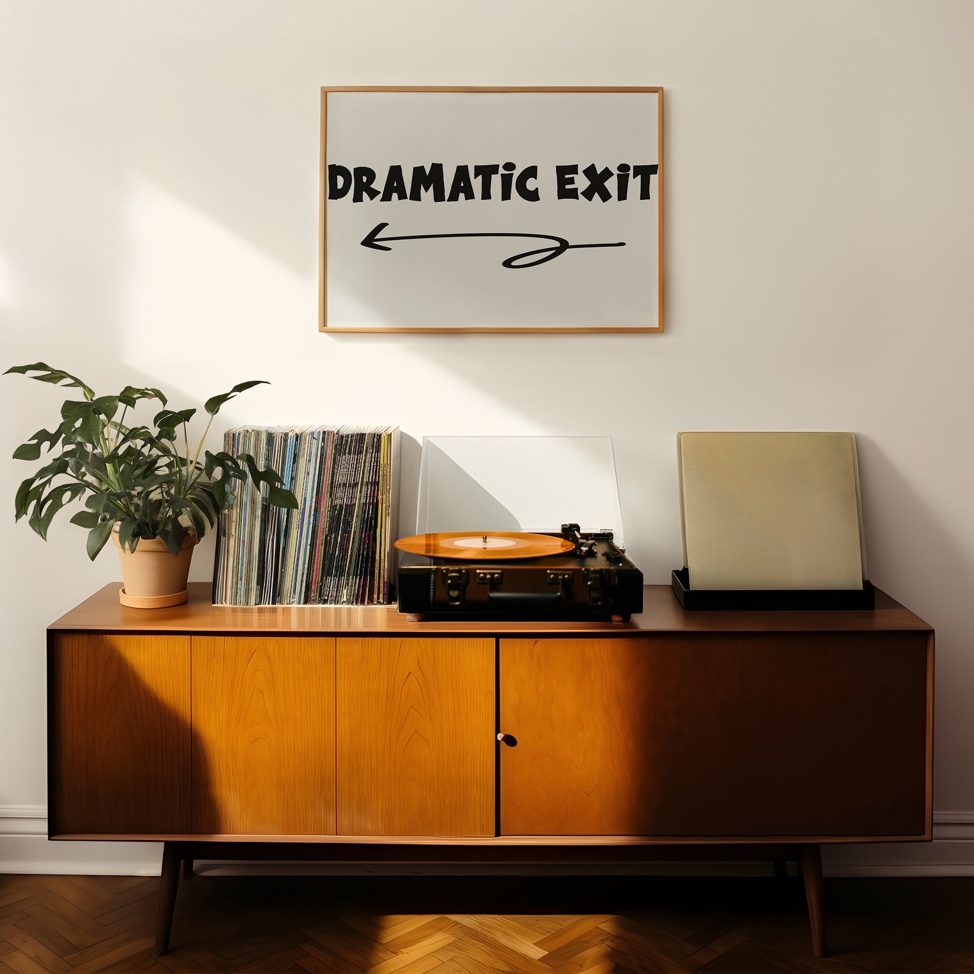 DRAMATiC EXiT LEFT poster with bold typography and left arrow above mid-century modern wooden console with records and plant.