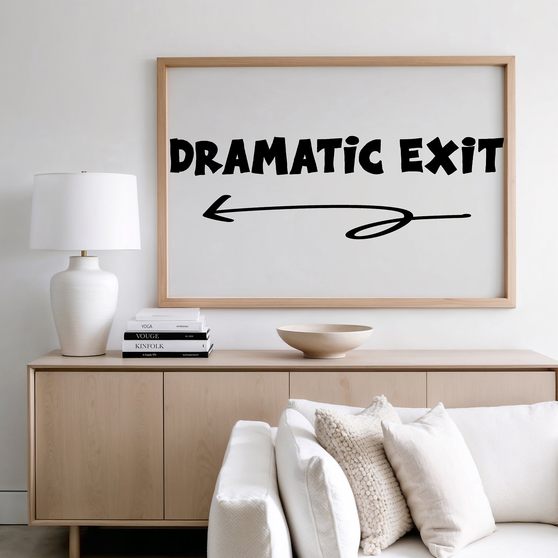 DRAMATiC EXiT LEFT poster with bold black typography and arrow, displayed in modern minimalist living room setting.