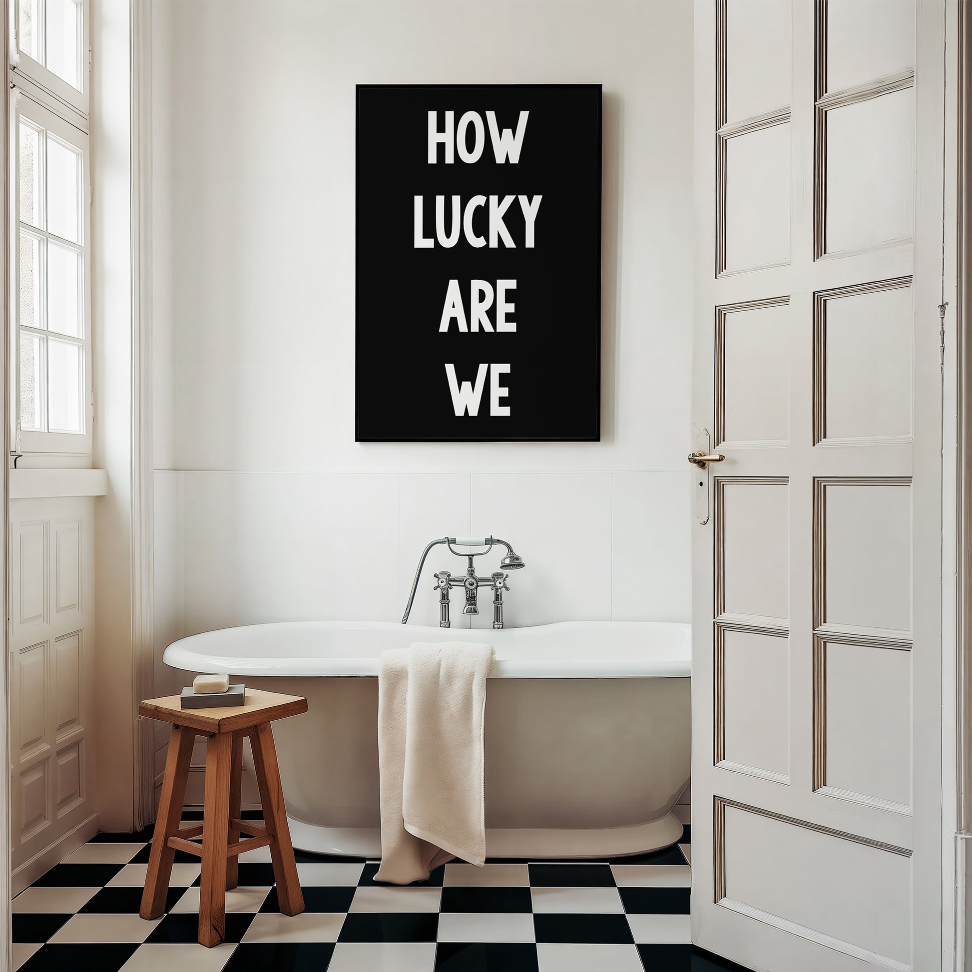 Black and white minimalist typography print poster "HOW LUCKY ARE WE" displayed in a modern bathroom setting.