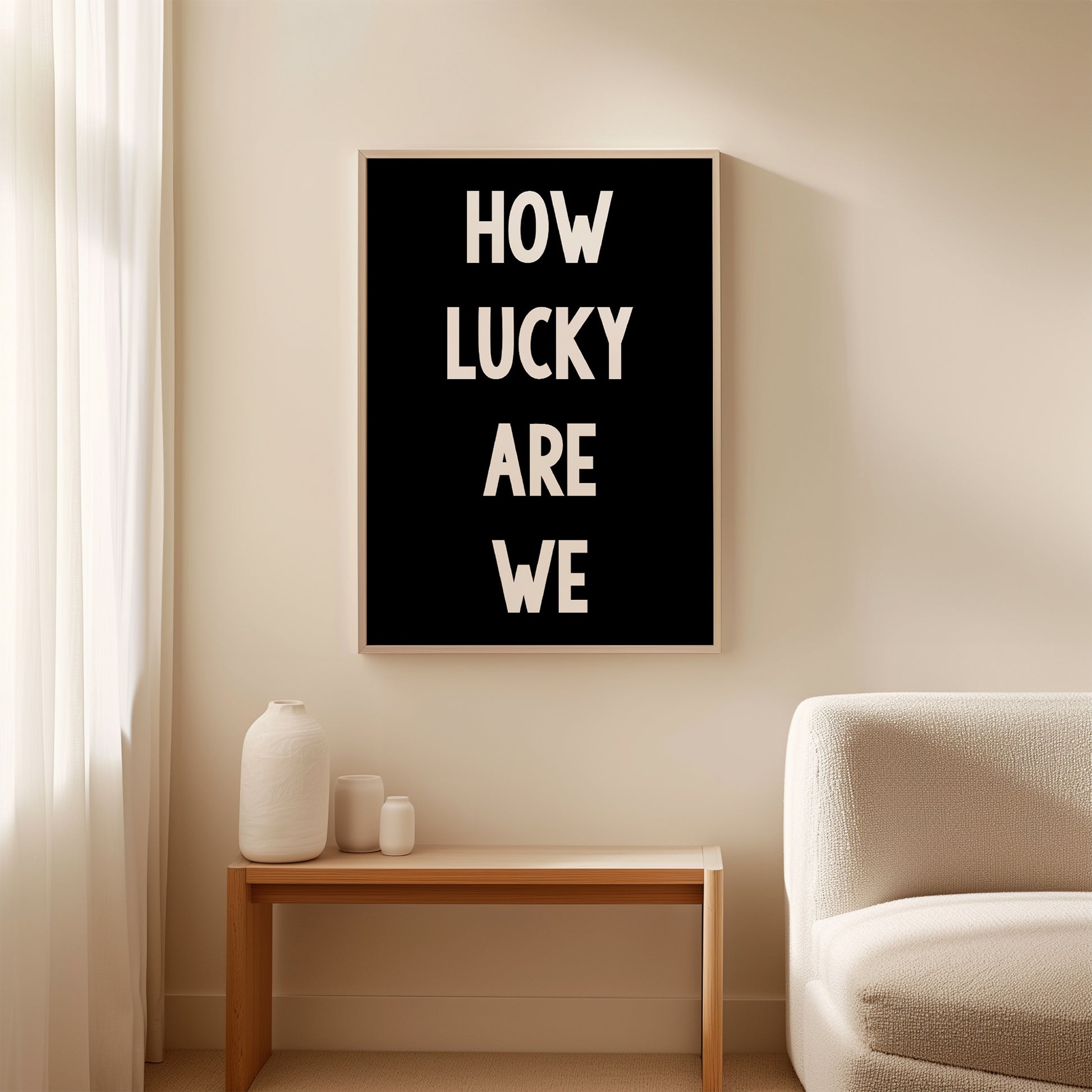 Black-and-white "HOW LUCKY ARE WE" typography poster hung in minimalist living space.