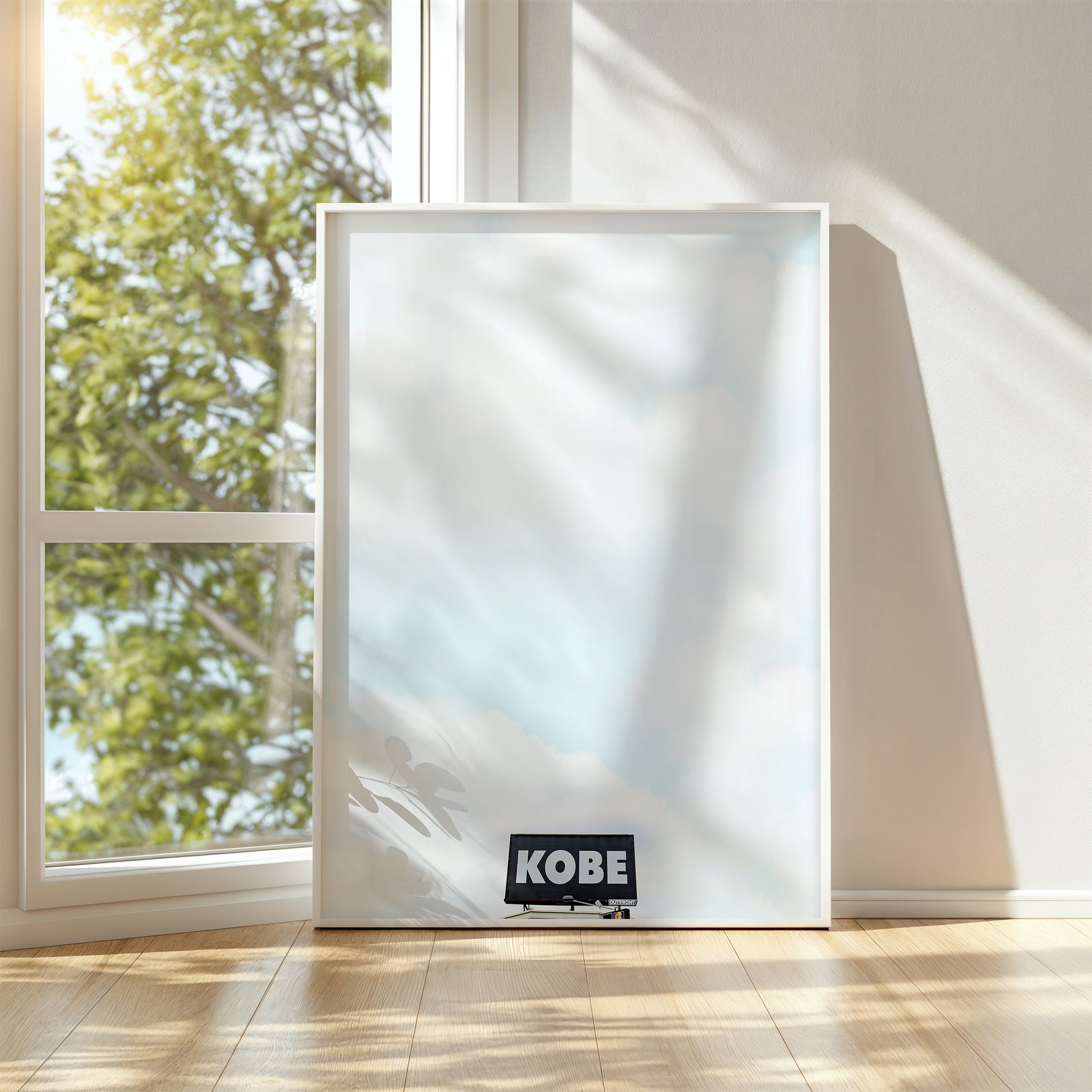 Minimalist KOBE photograph of a lone billboard against a vast cloudy sky, honoring Kobe Bryant's legacy.