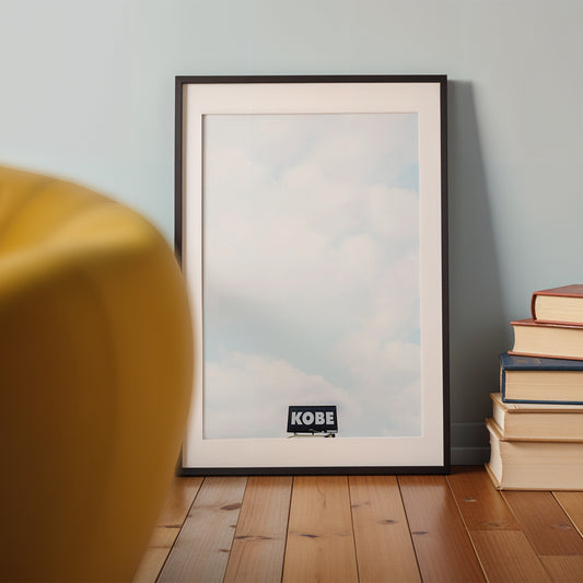 Framed minimalist photograph titled KOBE showing an urban billboard against a cloudy sky, perfect for modern spaces.