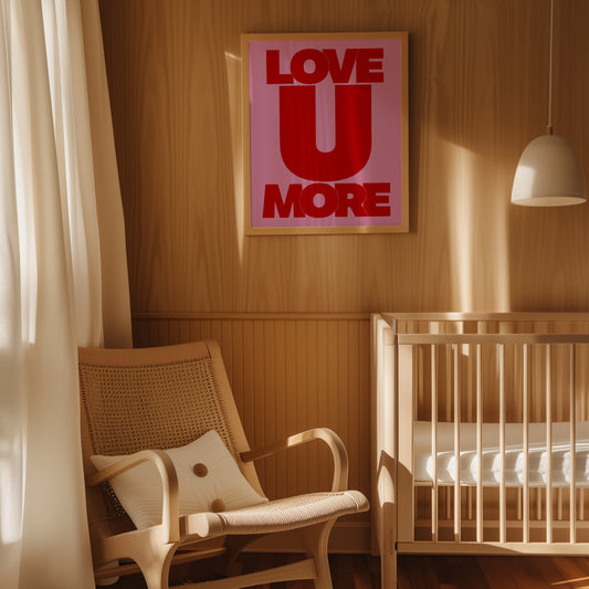 Framed "LOVE U MORE" poster with bold red text on pink background displayed in a cozy nursery room.