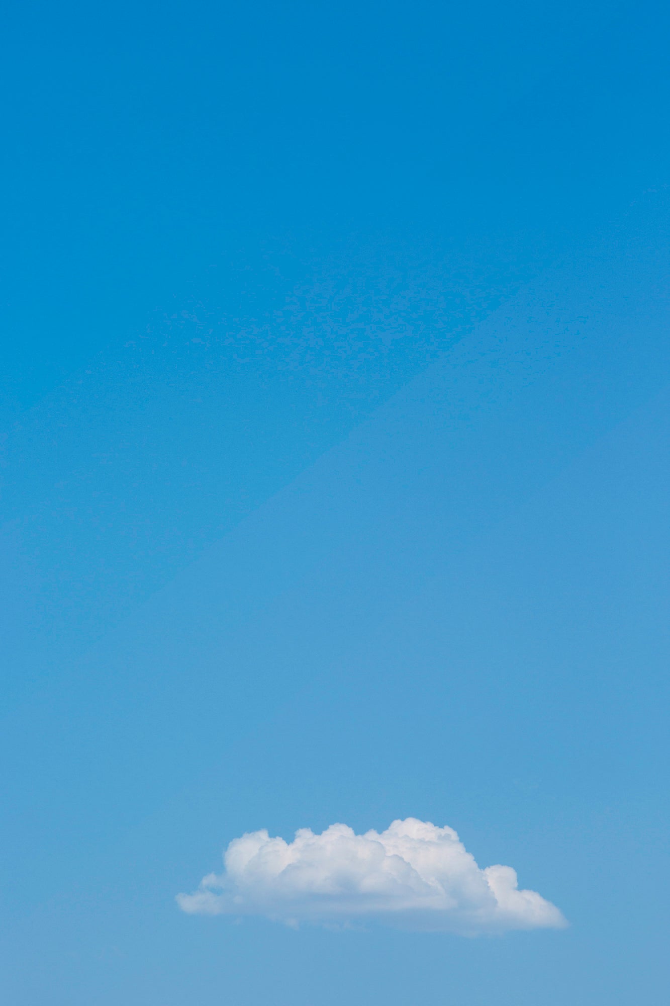 MEANWHiLE minimalist photograph of a single fluffy cloud in a clear blue sky, modern and calming wall art.