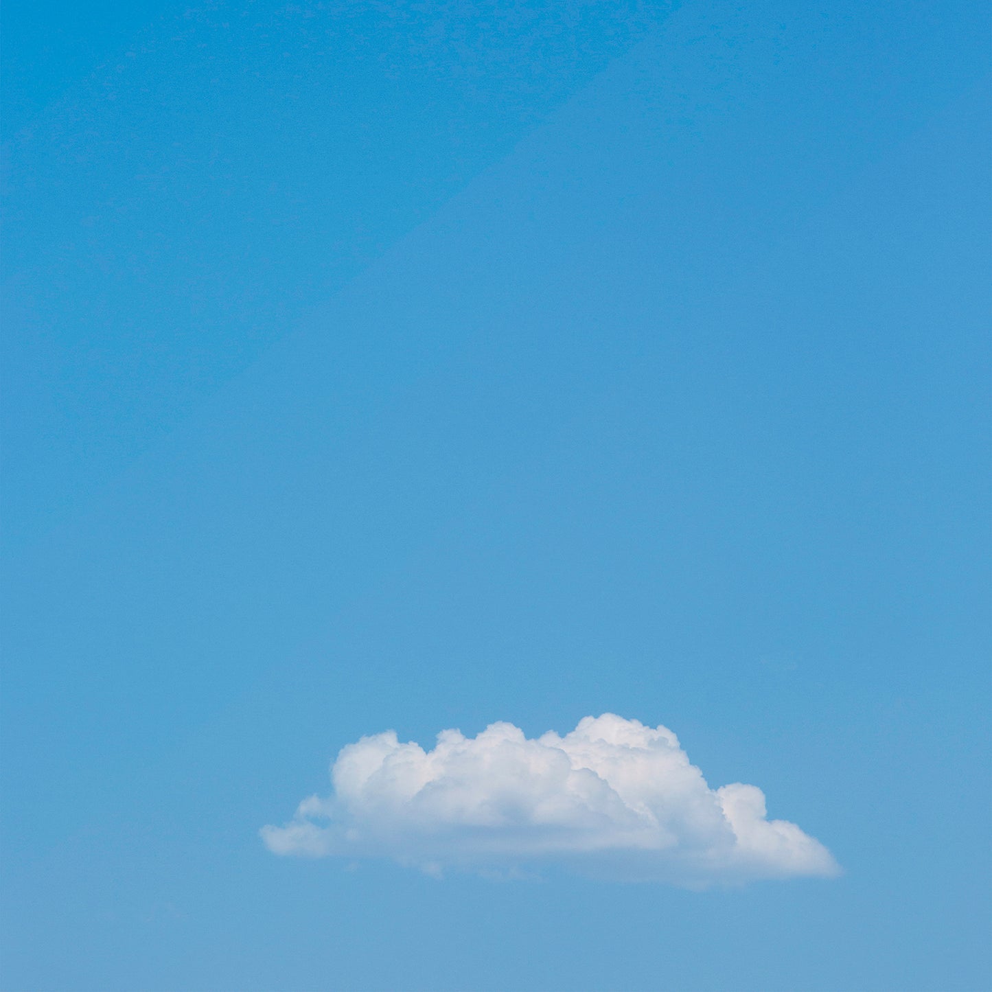 Minimalist photograph of a single fluffy cloud in a blue sky titled MEANWHiLE, perfect for calm, modern interiors.