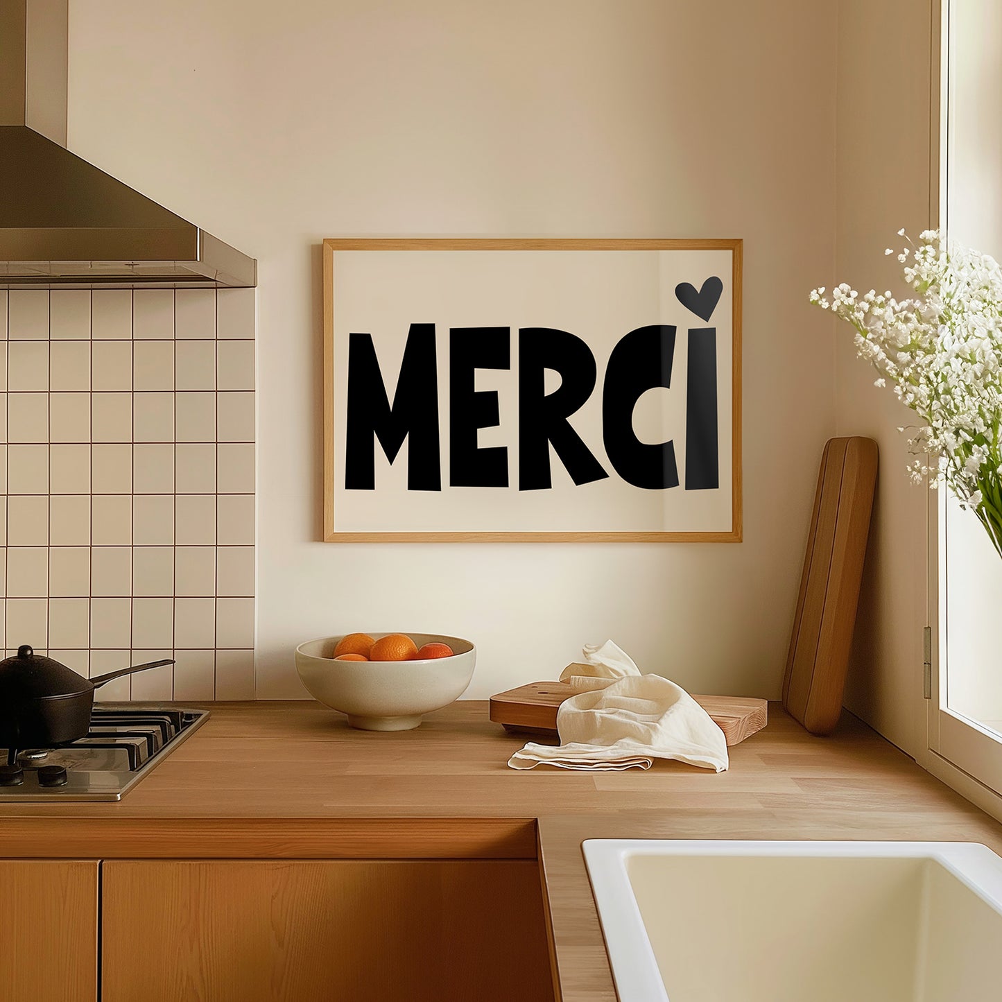 MERCi poster with bold black letters and heart dotting the i displayed in a modern kitchen setting.