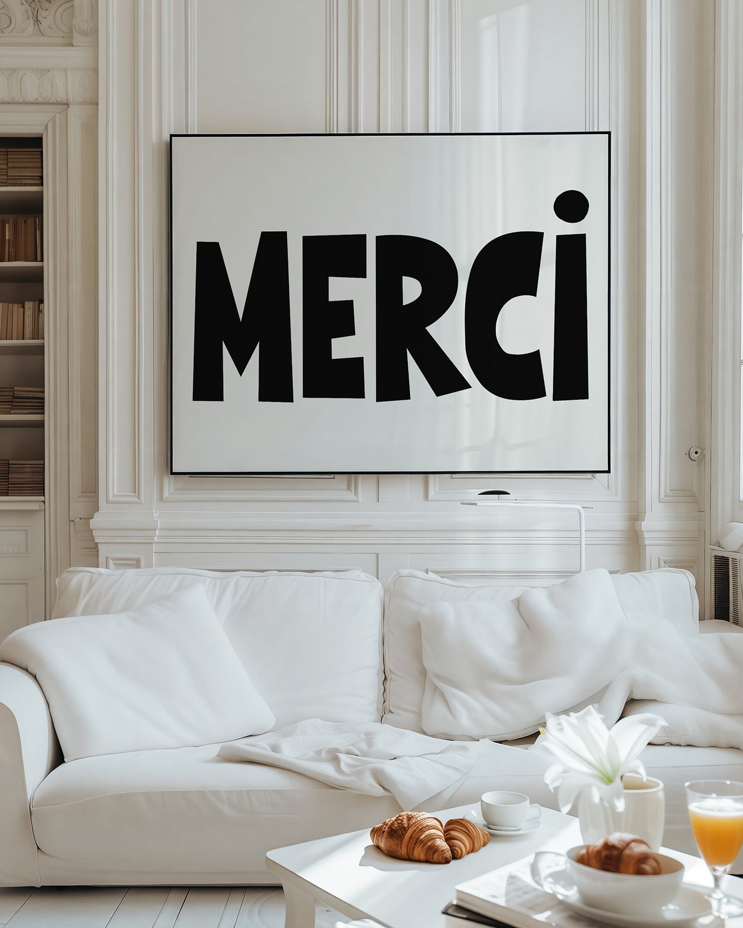 MERCi poster with bold black letters and heart dotting the i hanging above white sofa in bright living room.