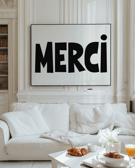 MERCi poster with bold black letters and heart dotting the i hanging above white sofa in bright living room.