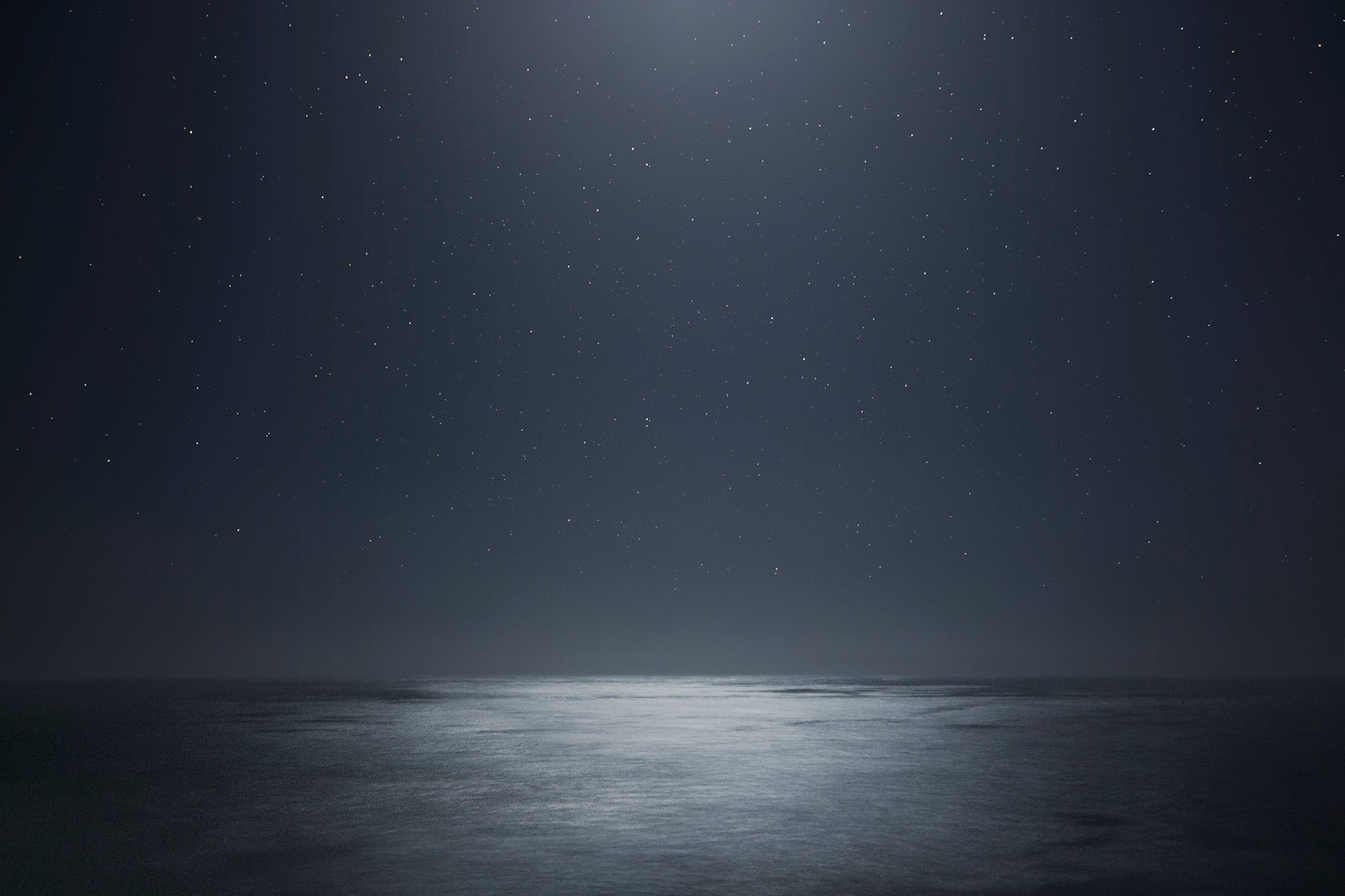 Dark ocean at night beneath a star-filled sky – moody, cosmic seascape photography