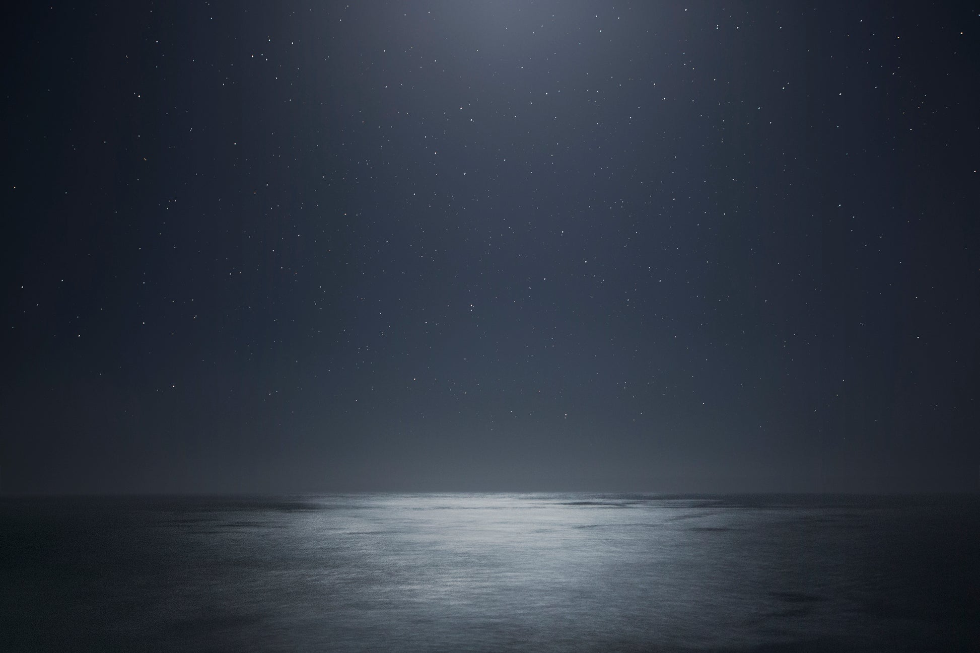 Dark ocean at night beneath a star-filled sky – moody, cosmic seascape photography