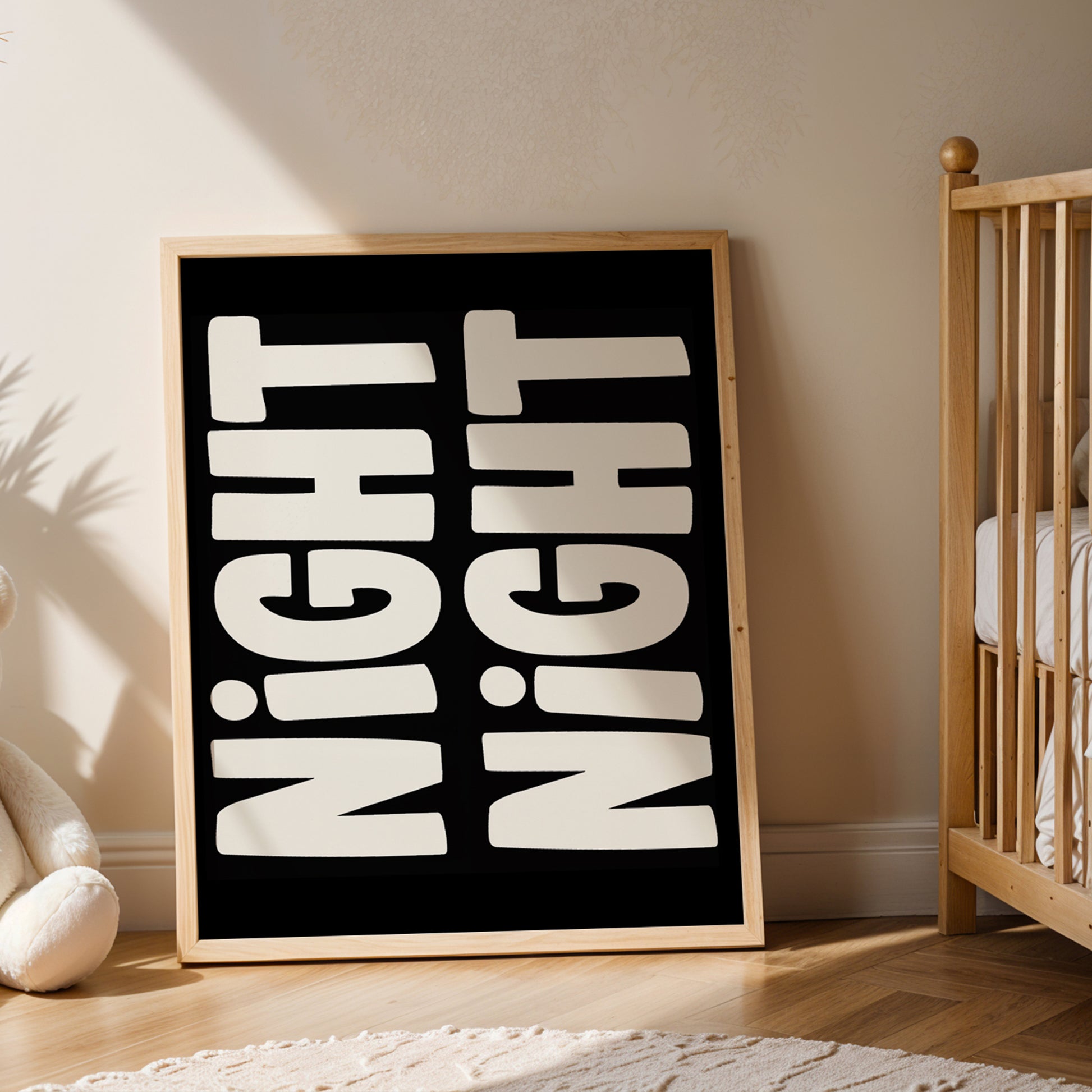 Framed "NiGHT NiGHT" black and off-white mirrored typography poster leaning in a cozy nursery room.
