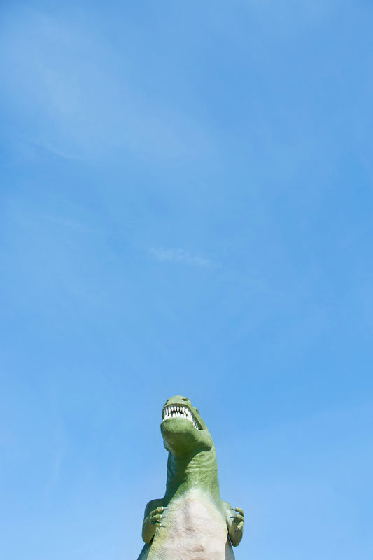 RAWR dinosaur statue against bright blue sky inspired by the RAWR kid-friendly decor print.