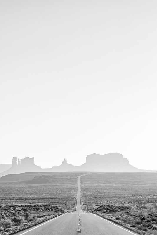 ROAD TRiP black-and-white photo of an open road leading to Monument Valley, symbolizing freedom and journey.