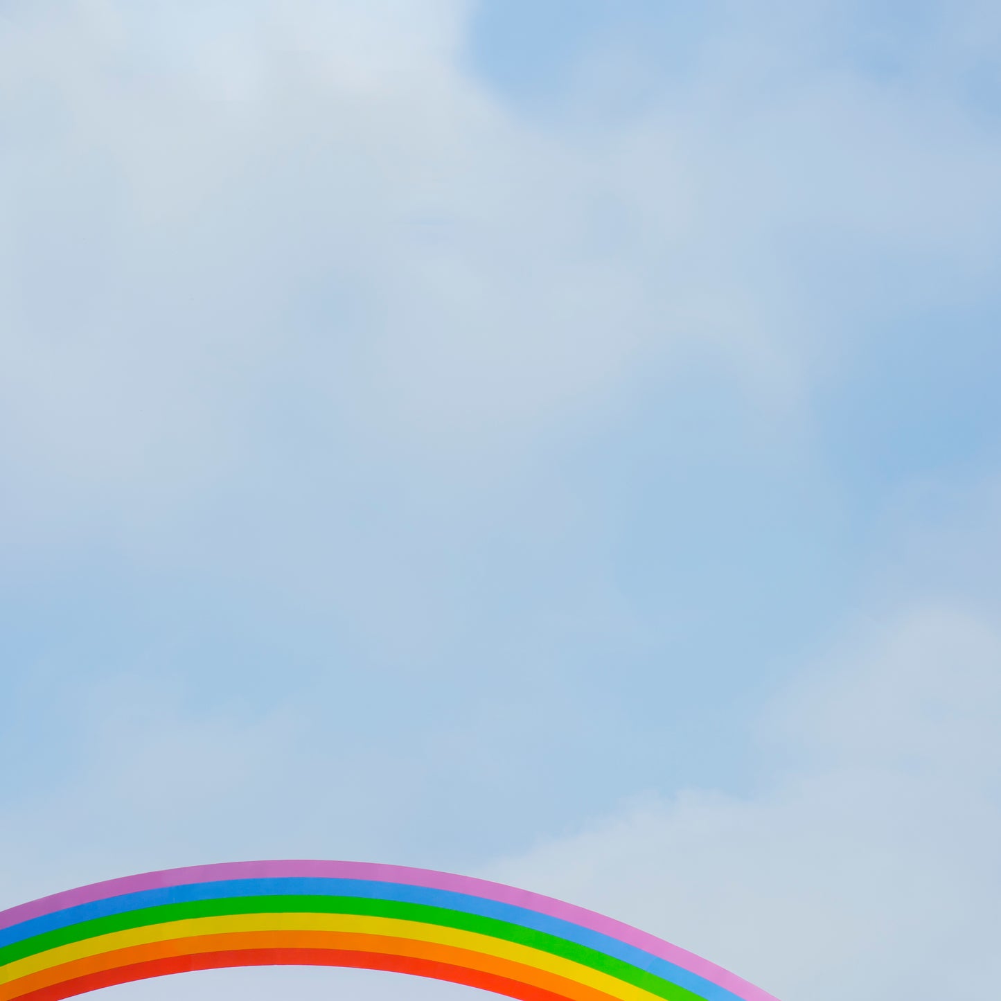 SOMEWHERE" bright rainbow arc peeking into soft cloud-filled blue sky, minimalist and uplifting artwork.