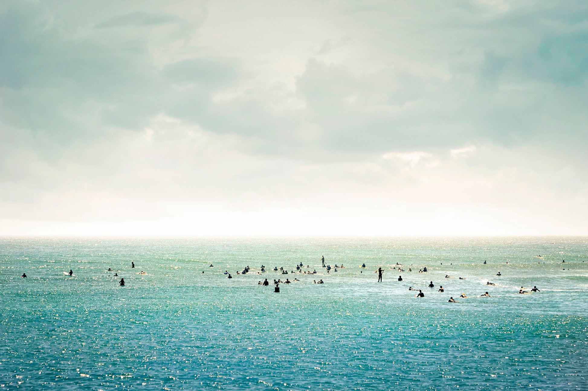 Group of surfers floating in calm water under soft pastel sky – peaceful ocean wall art