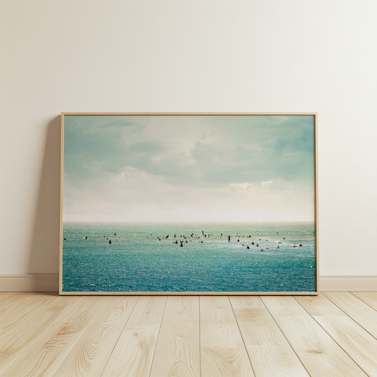 SURFRiDER ocean photo with surfers waiting for waves under moody skies, perfect for coastal wall decor.