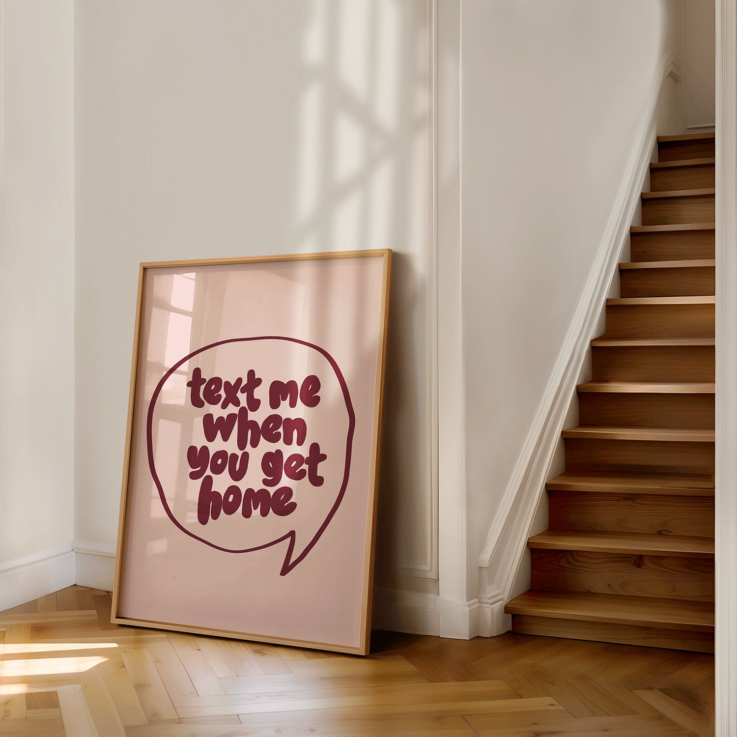 Framed poster "TEXT ME WHEN YOU GET HOME" with burgundy lettering in a speech bubble on a blush background.