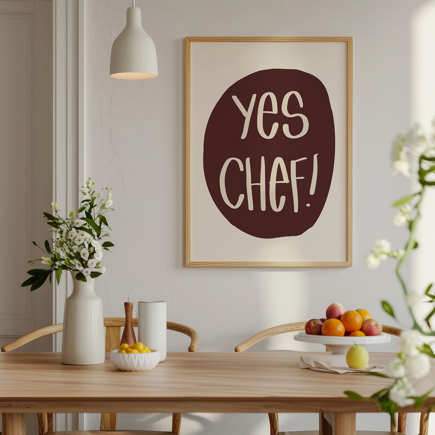 Framed "YES CHEF!" poster in maroon and cream displayed in a modern dining room setting.
