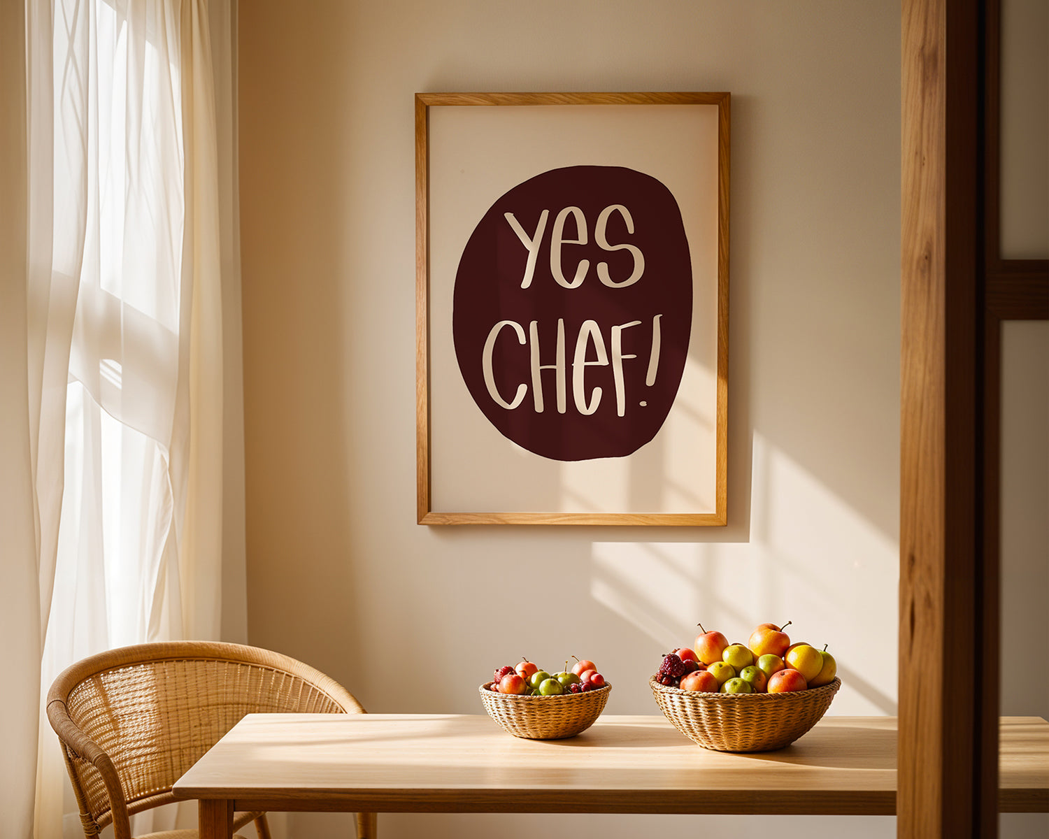YES CHEF! poster in maroon and cream framed on a wall above a wooden dining table with fruit bowls.