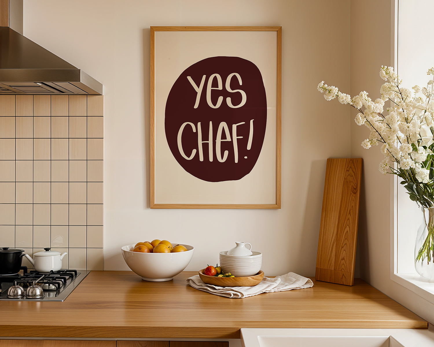 YES CHEF! poster with maroon and cream print in a modern kitchen setting above wooden countertop.