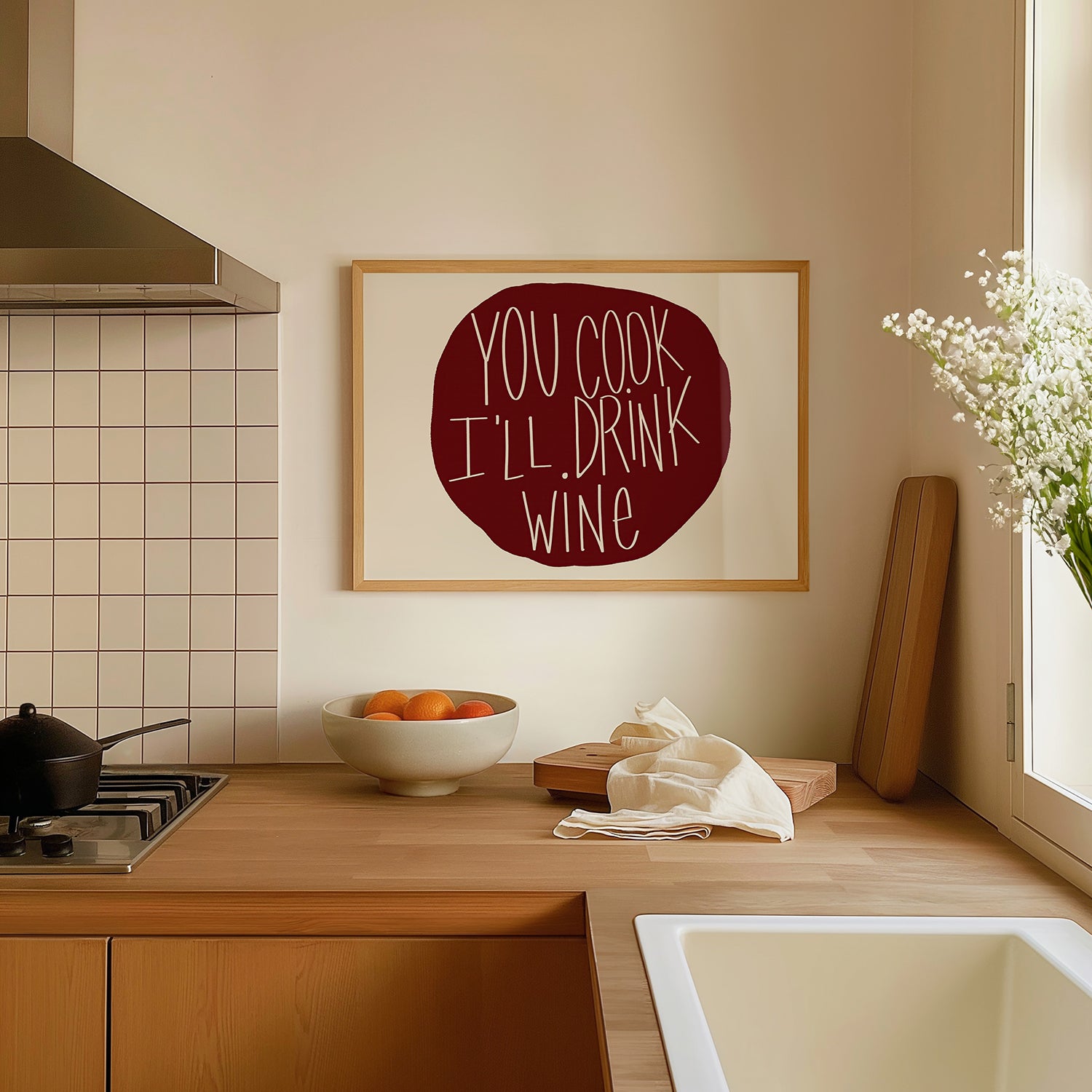 YOU COOK I'LL DRINK WiNE poster in burgundy typography displayed in a modern kitchen setting.