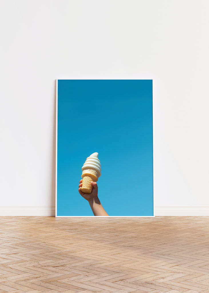 a child's hand and a soft serve ice cream cone against a blue sky