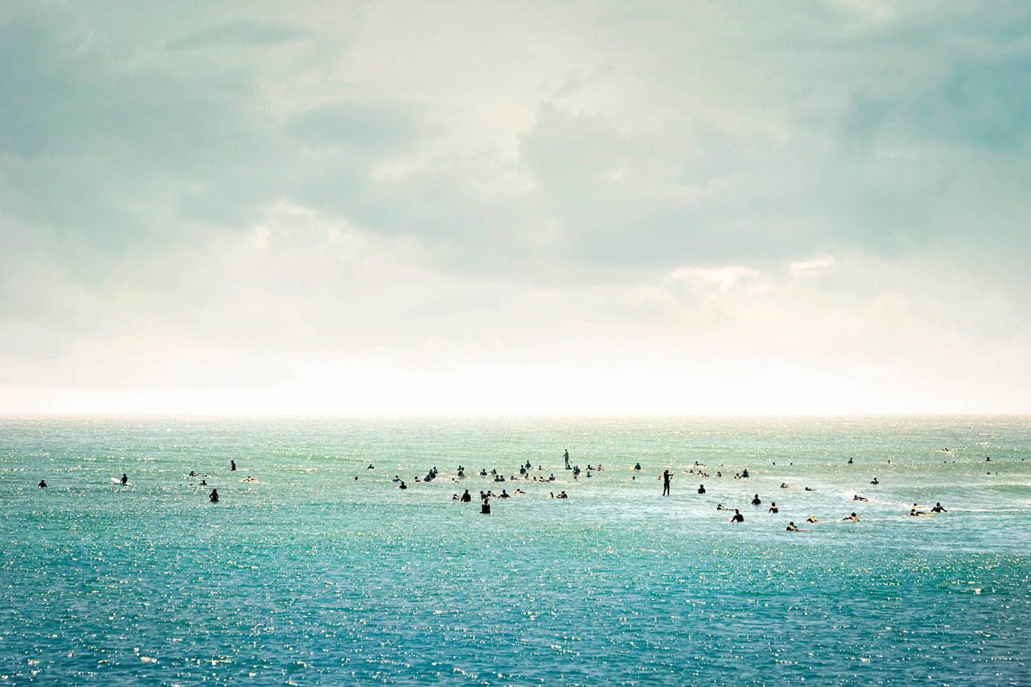 Group of surfers floating in calm water under soft pastel sky – peaceful ocean wall art