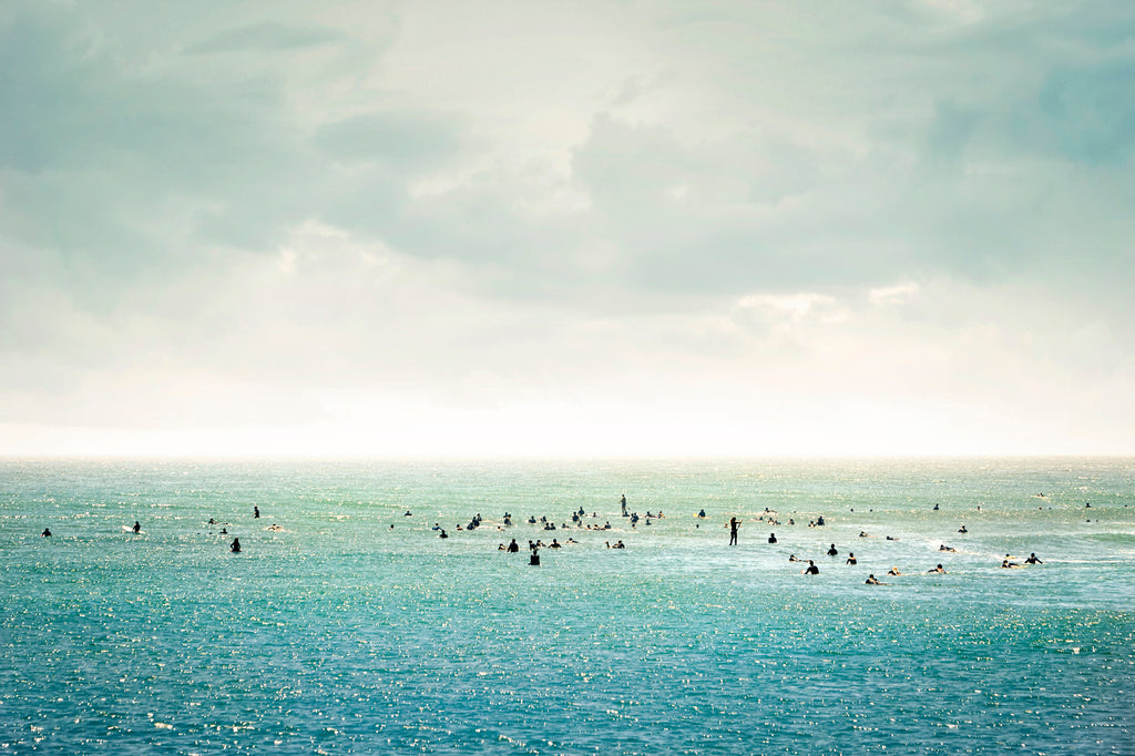 Group of surfers floating in calm water under soft pastel sky – peaceful ocean wall art