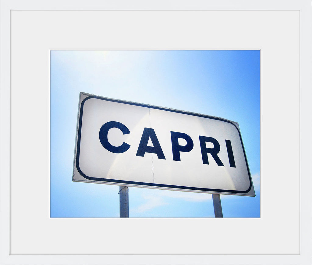 A minimal and modern image of the town sign in Capri, Italy against a blue sky streaked with sunlight. Available in square and horizontal formats in small and medium sizes. Printed on archival luster matte paper. - PRINTSHOP by Denise Crew