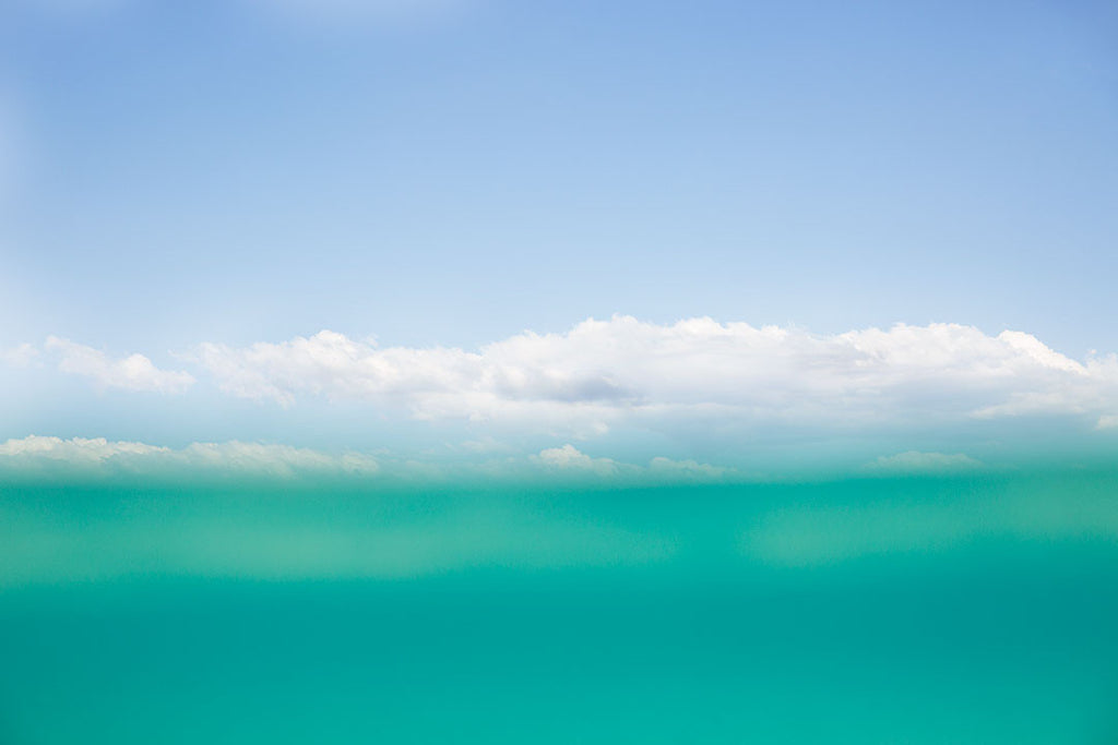 An abstract print with turquoise water and a blue sky with clouds available in square and standard formats. Vertical format available via custom order. Printed on archival luster matte paper. Available framed or unframed in standard photo sizes starting at 5x5 up to 30x45. - PRINTSHOP by Denise Crew